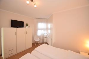 a white bedroom with a bed and a tv on a cabinet at Haus Ankerplatz Apartment 2 2 in Büsum