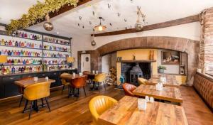 a restaurant with wooden tables and chairs and a fireplace at Gosforth Hall Inn in Gosforth