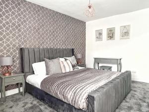 a bedroom with a large bed with a gray headboard at The Old Butchers Cottage in Matlock