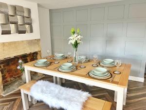 una mesa de comedor con platos y un jarrón de flores en The Old Butchers Cottage, en Matlock