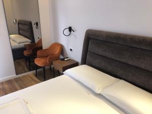 een slaapkamer met een bed, een stoel en een spiegel bij Skanderbeg Center Apartments 1 in Tirana