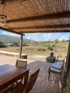 a wooden table and chairs under a wooden roof at dammuso dehors in Pantelleria