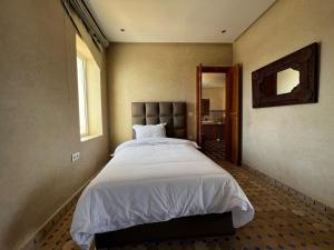 a bedroom with a large bed and a mirror at Les Ailes du sourire in Essaouira