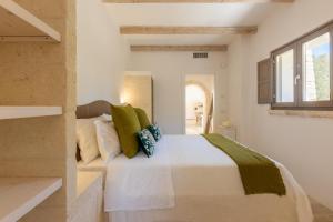 a bedroom with a white bed with green pillows at Lamia del Bosco con Piscina in Ostuni +36 photos