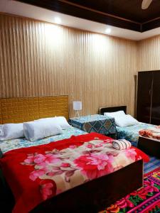 Un dormitorio con dos camas con flores. en Hikal Guest House, en Hunza