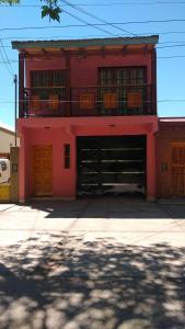 um edifício vermelho com duas portas de garagem e uma varanda em Departamentos PAEZ em Malargüe