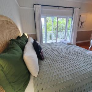Mount Glorious的住宿－Maiala Park Lodge，一间卧室配有带枕头的床铺和阳台