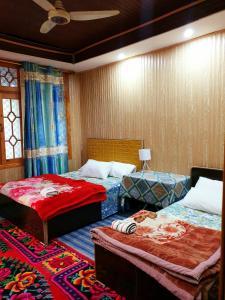 a bedroom with two beds and a rug at Hikal Guest House in Hunza Valley