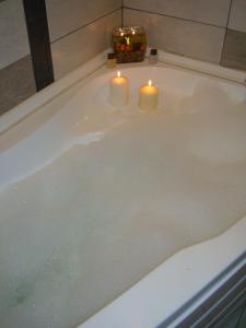 a bathtub with two candles and two candles in it at Guest House Lazur in Burgas City