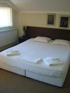 a large white bed with two towels on it at Guest House Lazur in Burgas City