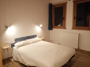 a bedroom with a white bed and two windows at Casa rural Lastoetxe in Larrauri