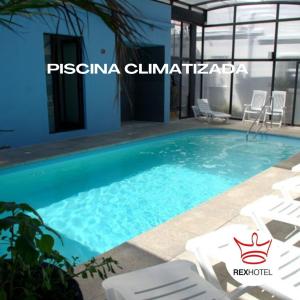 una piscina en una villa con sillas blancas en Hotel Rex, en Piriápolis