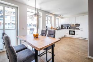 cocina y comedor con mesa de madera y sillas en Haus Hummerklippe Apartment 4, en Büsum