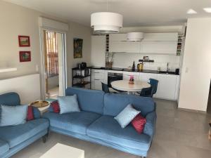 uma sala de estar com um sofá azul e uma cozinha em Superbe appartement T3 proche de la garrigue em Castries