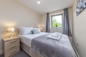 a bedroom with a bed with towels on it at Suites by Rehoboth - Palmers Green - London in London