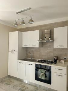- une cuisine avec des placards blancs et une cuisinière dans l'établissement Dea apartment, à Torre Annunziata