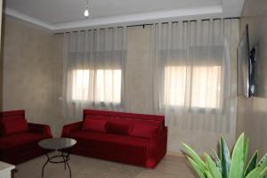 a living room with a red couch and two windows at Suites Appartement Midelt in Midelt