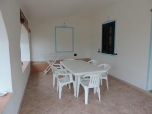 uma sala de jantar branca com uma mesa e cadeiras brancas em Residenza Su Portu em Orosei