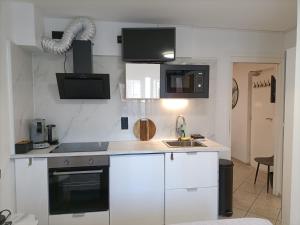 een keuken met witte kasten en een wastafel bij Pension Schier in Zandvoort