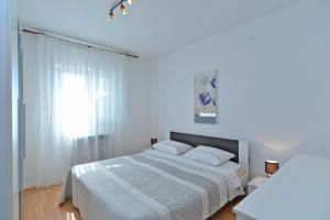ein weißes Schlafzimmer mit einem Bett und einem Fenster in der Unterkunft Apartments Mira 615 in Rovinj