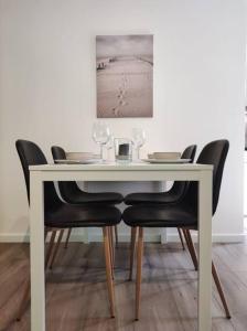- une table à manger avec des chaises noires et une table blanche dans l'établissement Central Apartment Flensburg, à Flensbourg