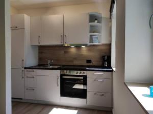 cocina con armarios blancos y fogones en Central Apartment Flensburg, en Flensburg
