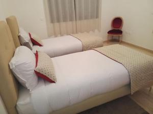 two twin beds in a room with a red chair at Suites Appartement Midelt in Midelt
