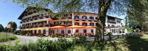 un gran edificio con mesas y sombrillas delante en Farbinger Hof, en Bernau am Chiemsee