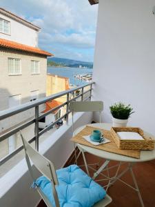 a table and chairs on a balcony with a view of the water at Combarro Suite in Combarro