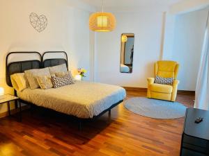 ein Schlafzimmer mit einem Bett und einem gelben Stuhl in der Unterkunft Combarro Suite in Combarro