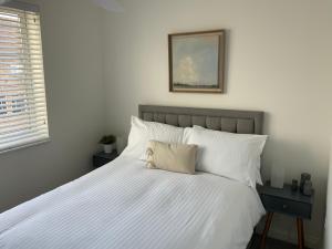 a bed with white sheets and a picture on the wall at Apartment #3 - at 12 Story St in Hull