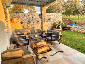 un patio con mesa, sillas y pared de piedra. en אחוזת היניבים Yaniv Estate, en Nurit