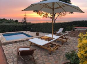un patio con ombrellone, sedie e piscina di VILLA ALICE-INFINITYHOLIDAYS a Costa Paradiso