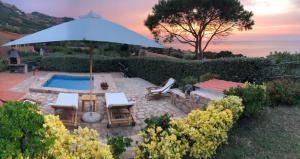 un patio con ombrellone, sedie e piscina di VILLA ALICE-INFINITYHOLIDAYS a Costa Paradiso