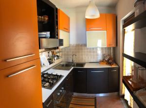 una piccola cucina con armadi arancioni e lavandino di VILLA ALICE-INFINITYHOLIDAYS a Costa Paradiso