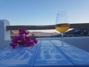 un bicchiere di vino seduto su un tavolo con fiori viola di Evilou's House a Krotiri