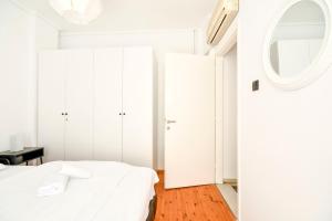 - une chambre blanche avec un lit et un miroir dans l'établissement Thessaloniki City Apartment Center, à Thessalonique