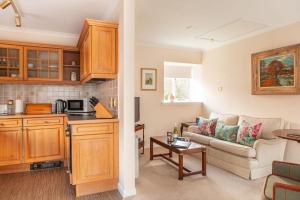 een keuken en een woonkamer met een bank bij Balnagown Estates Peat Cottage in Kildary