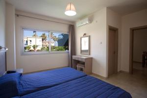 a bedroom with a blue bed and a window at Makronisos Village in Ayia Napa