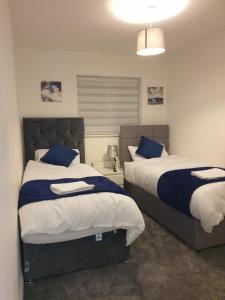 um quarto com 2 camas com almofadas azuis e brancas em Cheerful 4 Bedroom Townhouse with free parking em Kenton