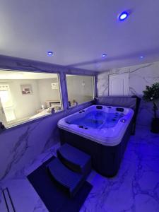 a large bathroom with a large tub with blue lighting at Spa Apartment in Saint-Maurice