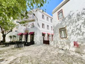 a white building with tables and chairs in front of it at Vila Rosário 3 studios with Patio by Homeful Homes in Lisbon