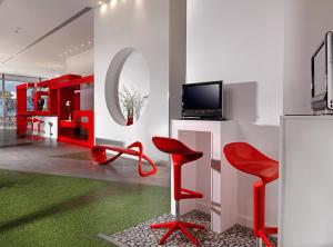Il comprend un salon doté de fauteuils rouges et d'une télévision. dans l'établissement Airotel Patras Smart Hotel, à Patras
