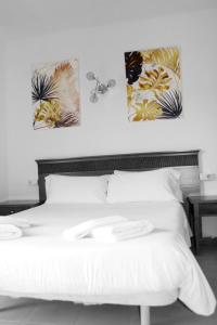 a bedroom with a white bed with two pictures on the wall at Apartamentos Gomila Park in Palma de Mallorca