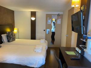 um quarto de hotel com duas camas e uma secretária em SHELDER Hôtel - CHERBOURG EN COTENTIN - Equeurdreville em Cherbourg en Cotentin