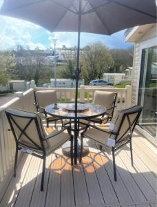 une table et des chaises sur une terrasse avec un parasol dans l'établissement Static Caravan to Hire , Hoburne Devon Bay ( Paignton), à Goodrington
