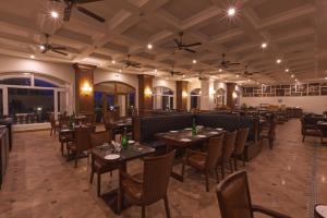 Montrose Golf Resort and Spa - Coorg في Jambur: مطعم يحتوي على طاولات وكراسي في الغرفة