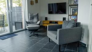 duas cadeiras e uma televisão numa sala de estar em Haus Nordseeliebe mit Außensauna, Outdoor Dusche und Wallbox em Dornum
