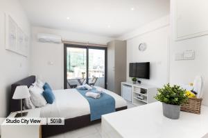 um quarto branco com uma cama e uma televisão em Lazuli City & Seaview Apartments em Lárnaca