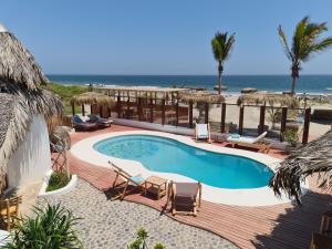 a swimming pool with chairs and the ocean in the background at Maracol Bungalows Vichayito in Vichayito